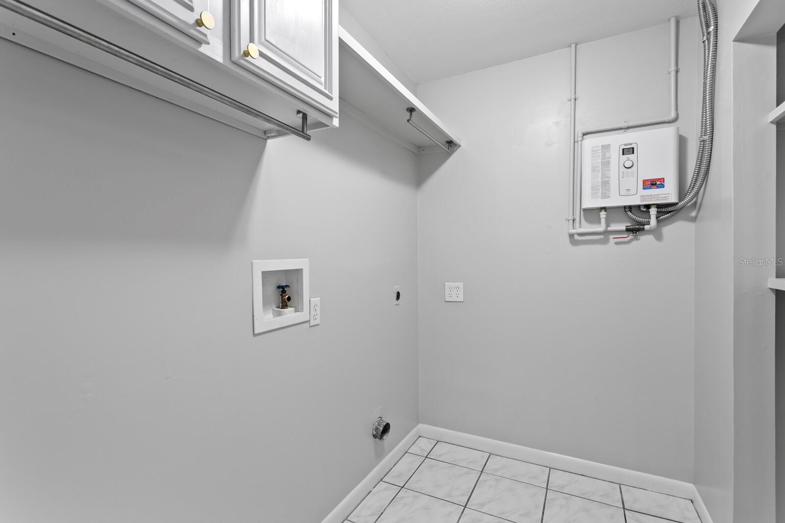 Inside utility room with cabinet storage and tankless water heater