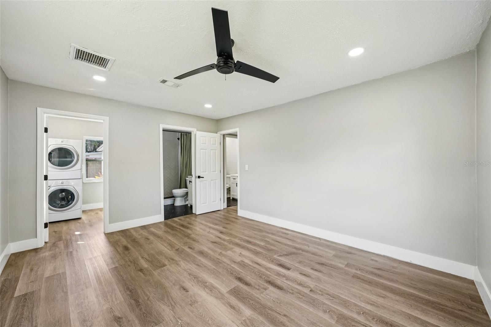 The primary bedroom offers generous space, recessed lighting, a walk-in closet, and an ensuite bathroom. Both bathrooms feature modern finishes, including a sleek vanity with an LED mirror, and a gleaming tiled shower with contemporary accents.
