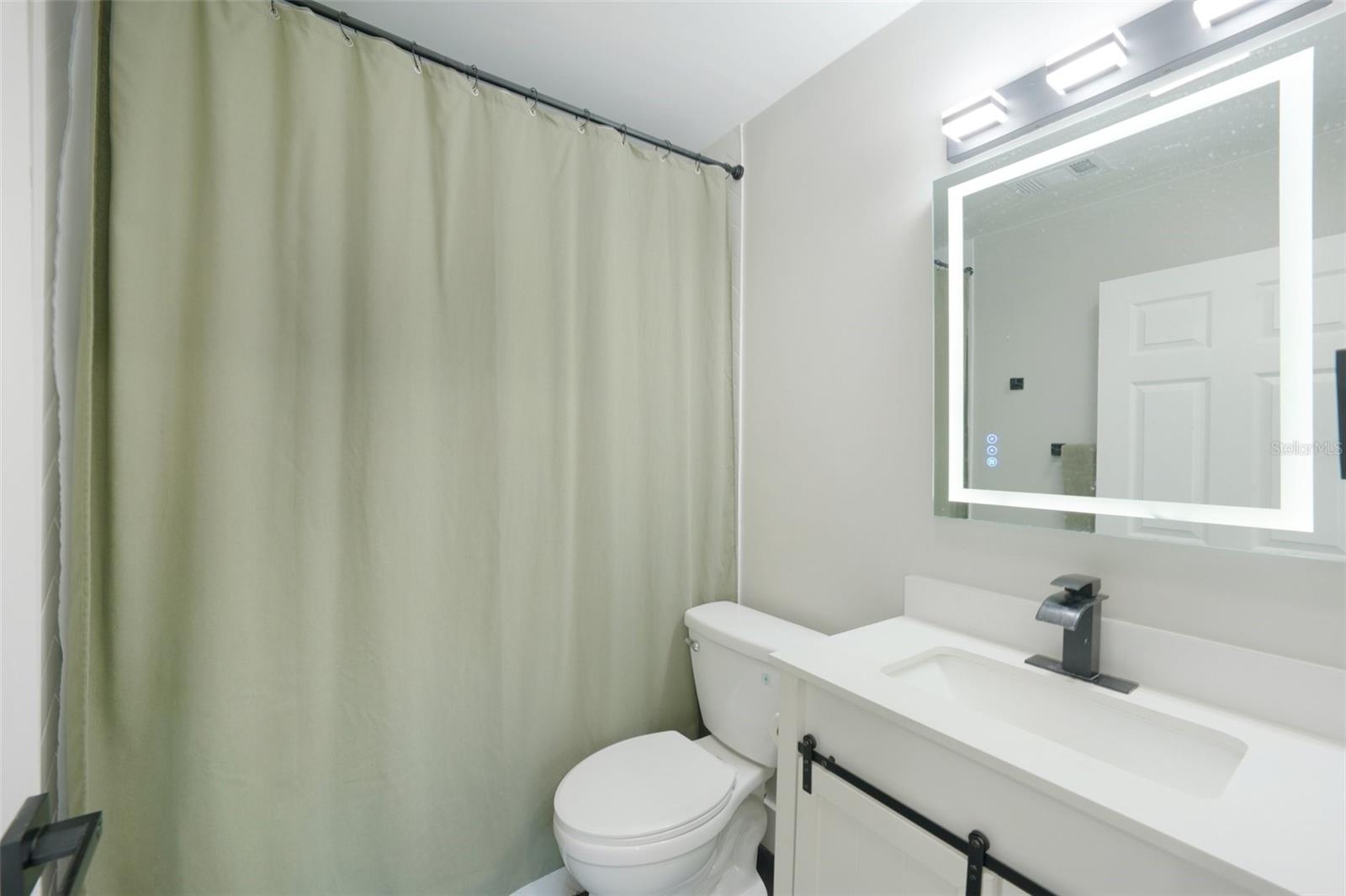 Primary ensuite bathroom features modern finishes, including a sleek vanity with an LED mirror, and a gleaming tiled shower with contemporary accents