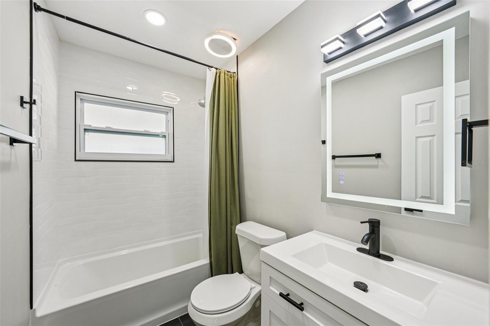 Second Bathroom features modern finishes, including a sleek vanity with an LED mirror, and a gleaming tiled shower with contemporary accents
