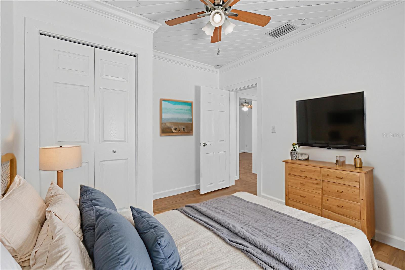 Comfortable guest room with wood-look flooring, ceiling fan, and plenty of natural light.