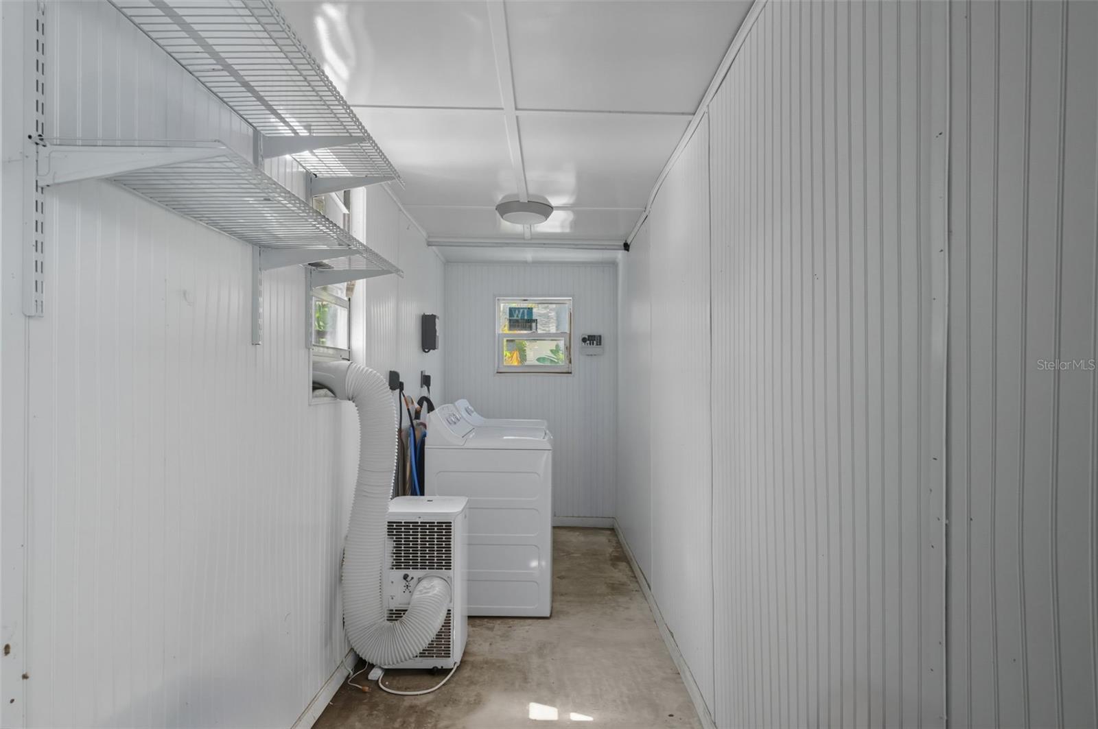 Dedicated laundry space with storage shelving and natural light.
