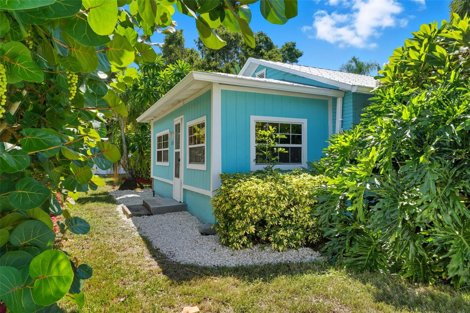 Surrounded by lush tropical landscaping, this coastal cottage offers privacy and curb appeal in a vibrant golf cart community.