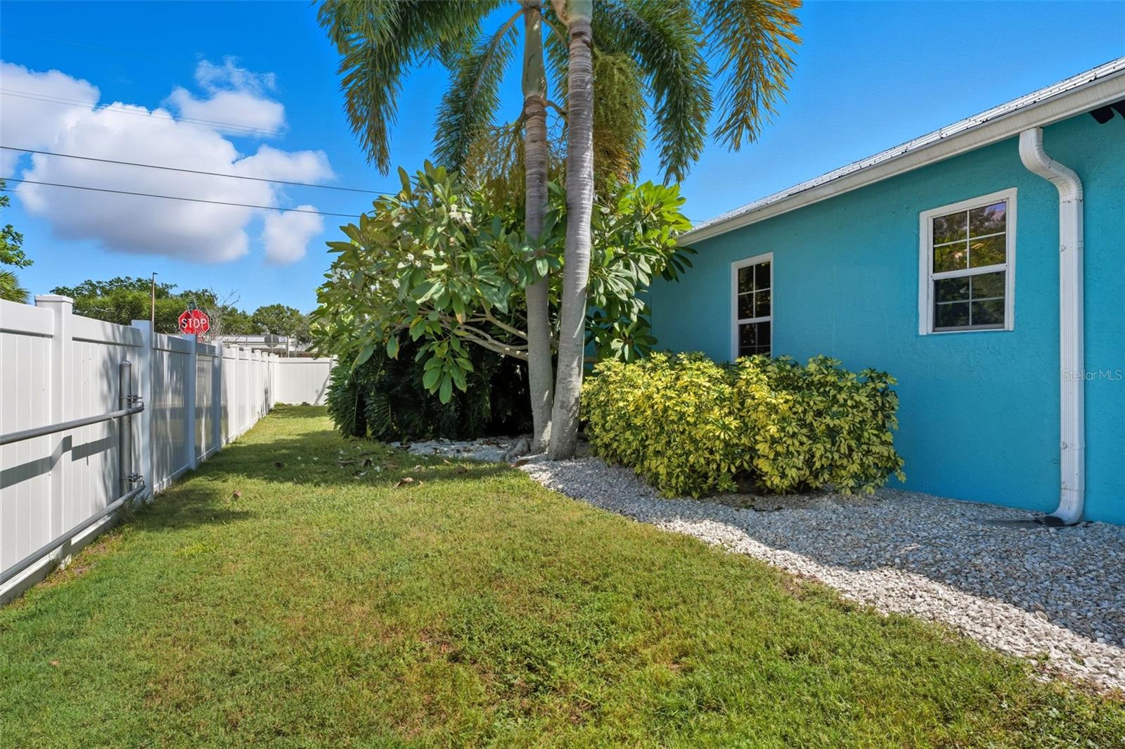 Extra green space with low-maintenance rock beds and mature palms enhancing the coastal curb appeal.