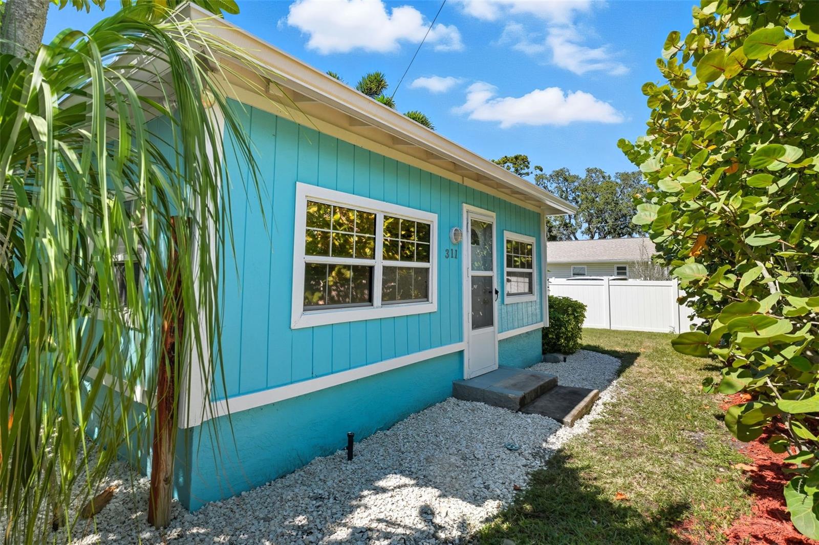 Bright aqua exterior accented by mature greenery creates a cheerful Florida look.