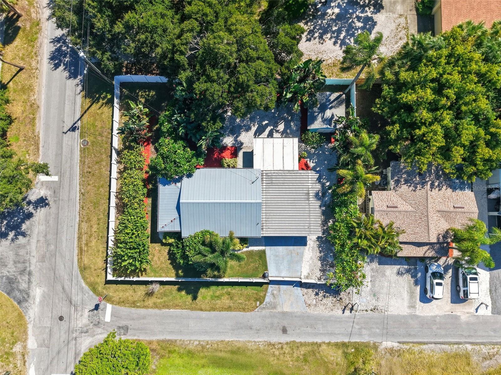 Fully fenced corner lot with tropical landscaping and ample outdoor space for entertaining or storage.