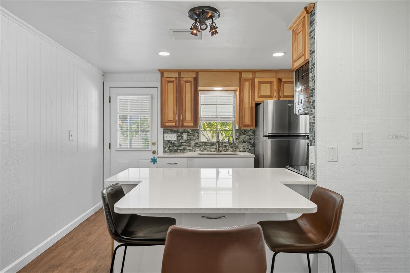 Renovated kitchen with breakfast bar seating, granite-look counters, and modern appliances.