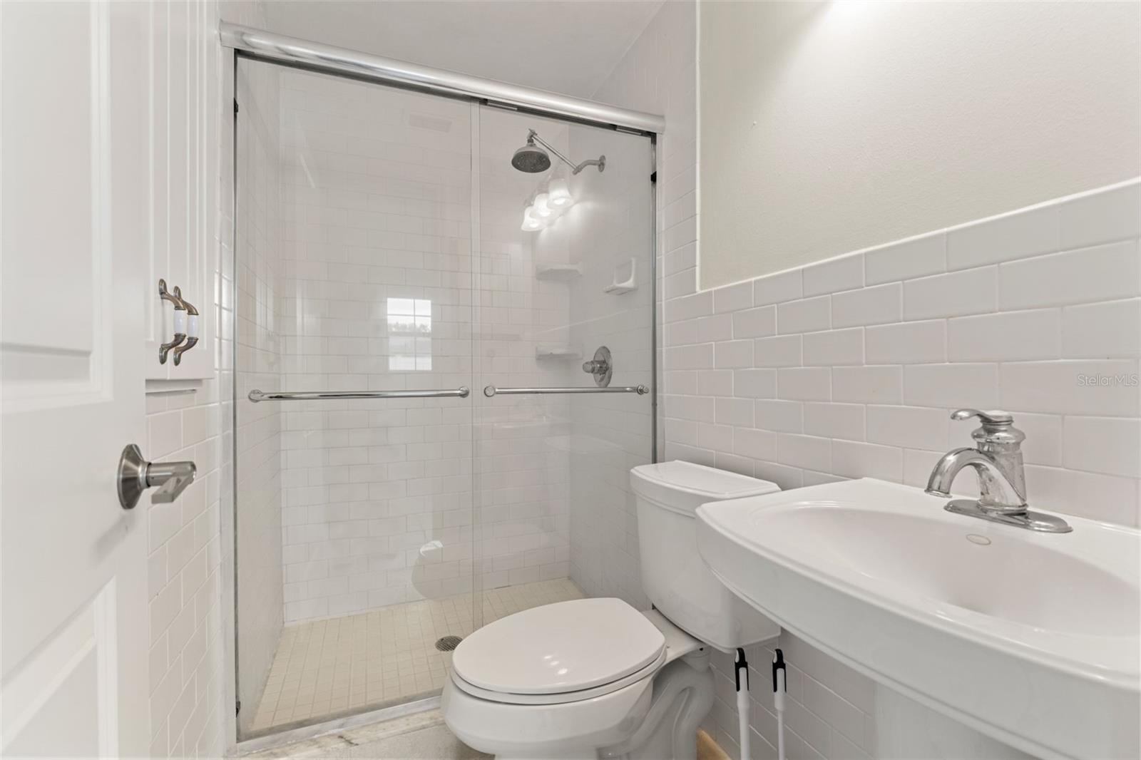 Stylishly updated with subway-tile shower, glass enclosure, and a sleek pedestal sink.