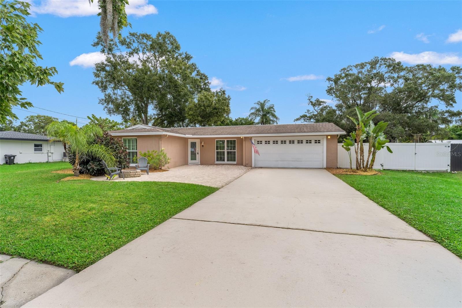 Impeccably maintained single-story home with lush green lawn, paver patio, and fenced yard offering both charm and privacy.