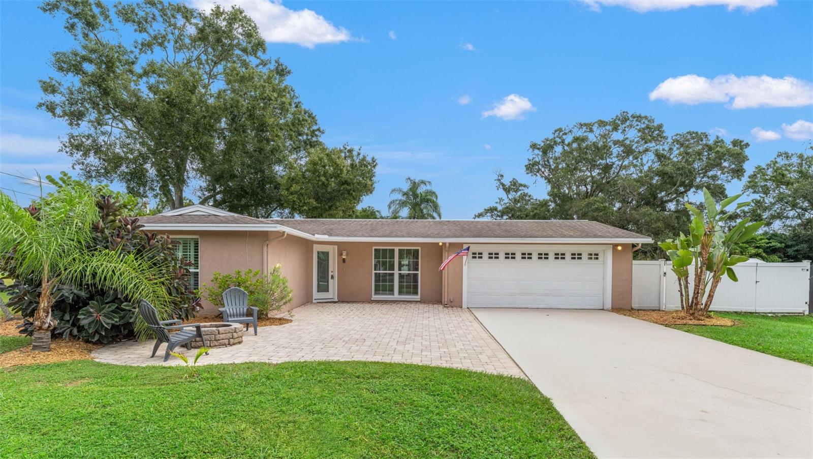 A spacious concrete drive leads to a two-car garage and freshly mulched landscaping, providing plenty of space for guests or recreational parking.