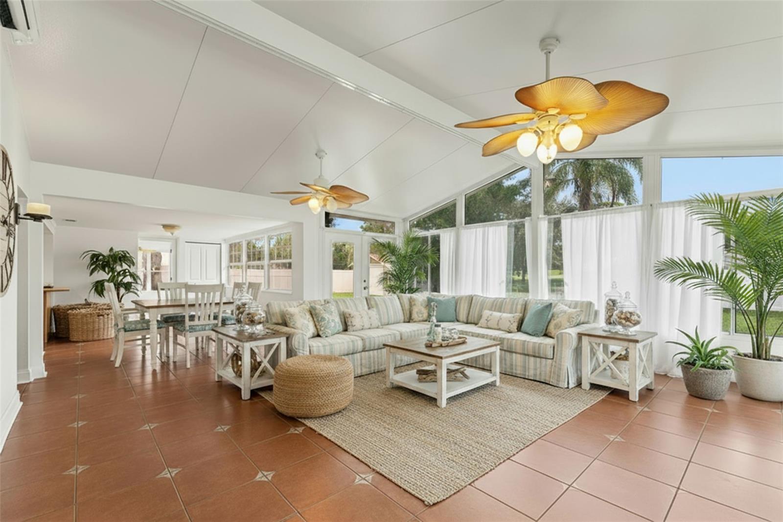 Expansive gathering area with vaulted ceilings, walls of glass, and tile flooring—perfect for relaxing or entertaining while enjoying views of the backyard.