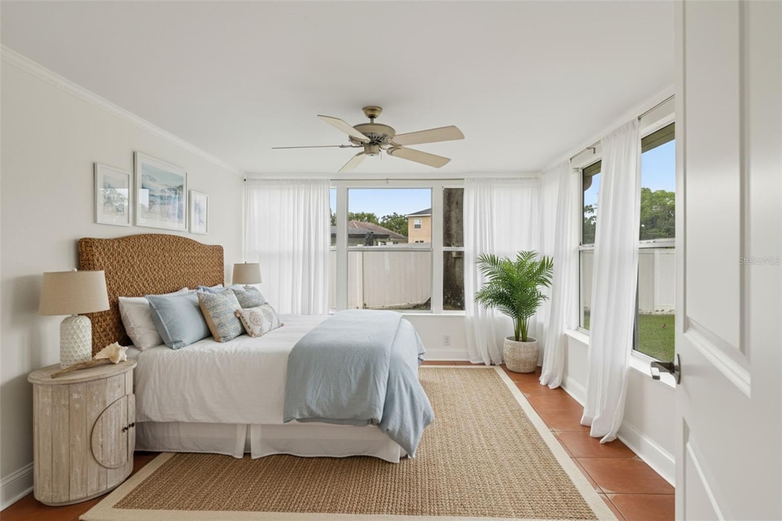 4th bedroom is a sun-filled retreat featuring wraparound windows, neutral tones, and airy drapery that enhances the sense of space and serenity.