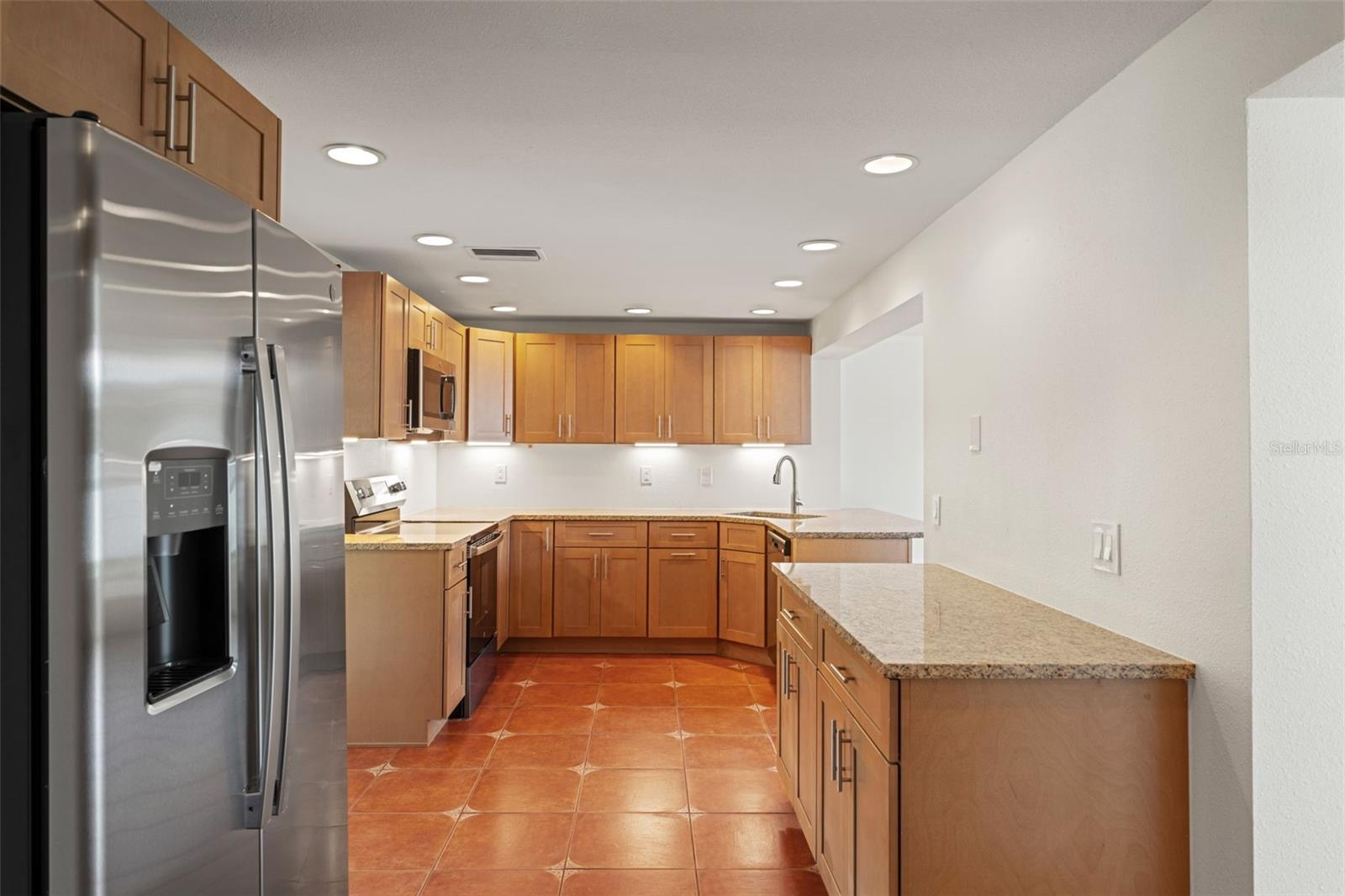 A true chef’s kitchen with stainless steel appliances, granite countertops, and solid maple cabinetry offering abundant storage and workspace.