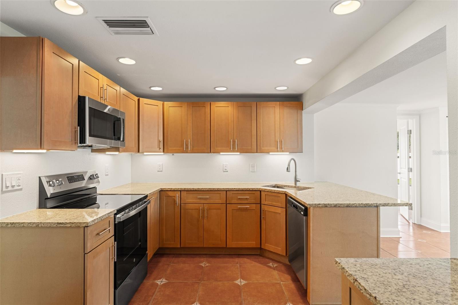 Open-concept layout offers generous prep space and a seamless connection to the dining area and sunroom beyond.