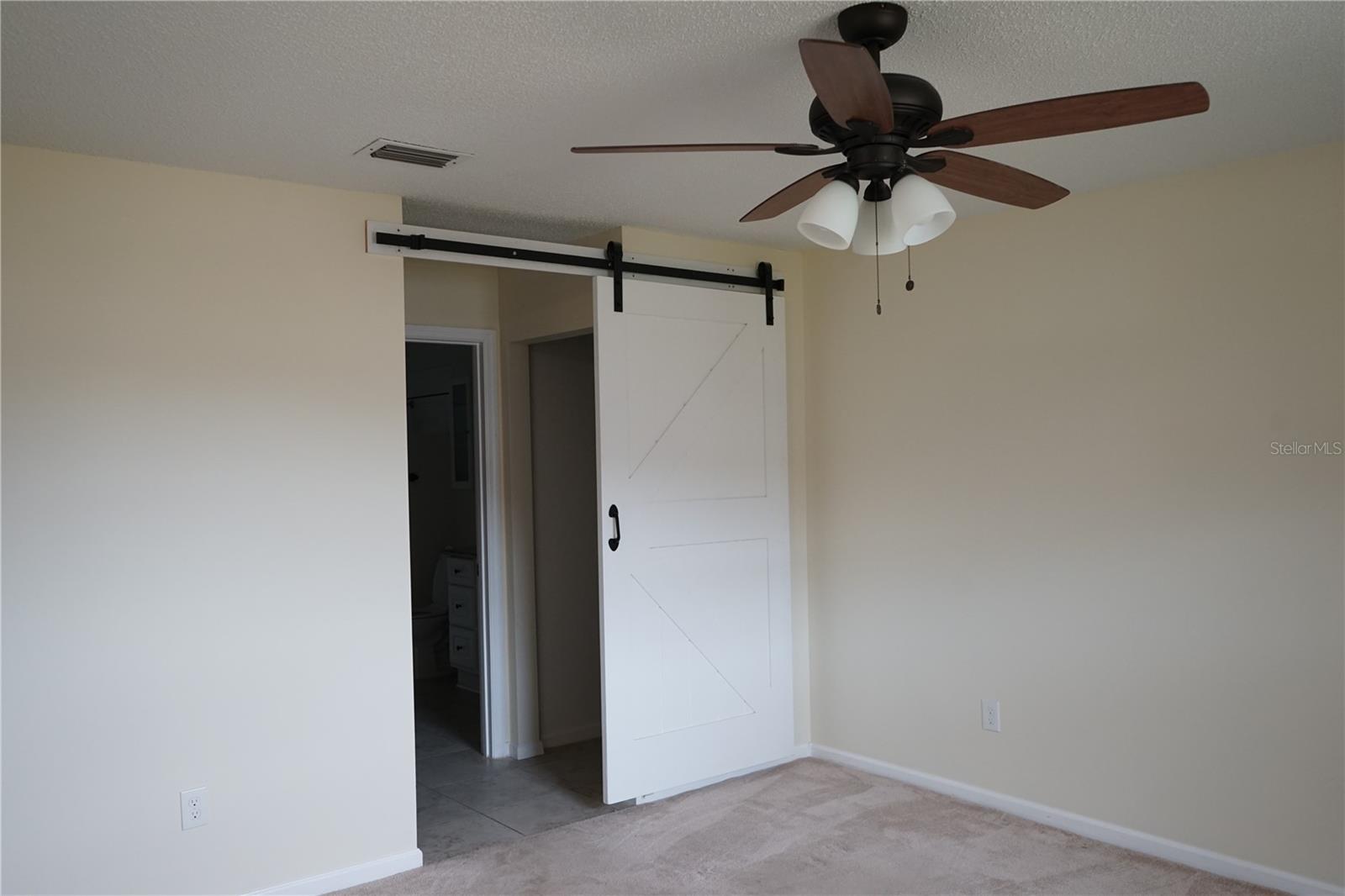 primary bedroom has barn door to closets and bathroom