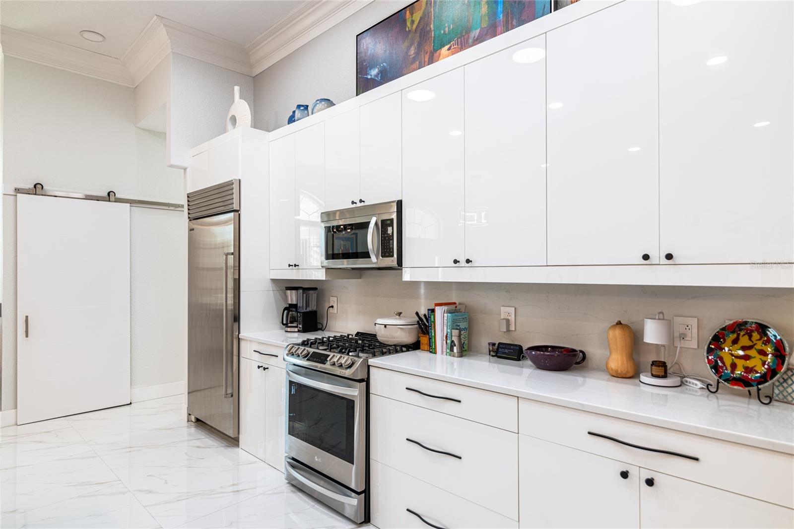 KITCHEN AREA VIEW WITH GAS OVEN AND MICROWAVE AND SUB-ZERO REGRIGERATER - WOOD CABINETS - QUARTZ COUNTERTOPS