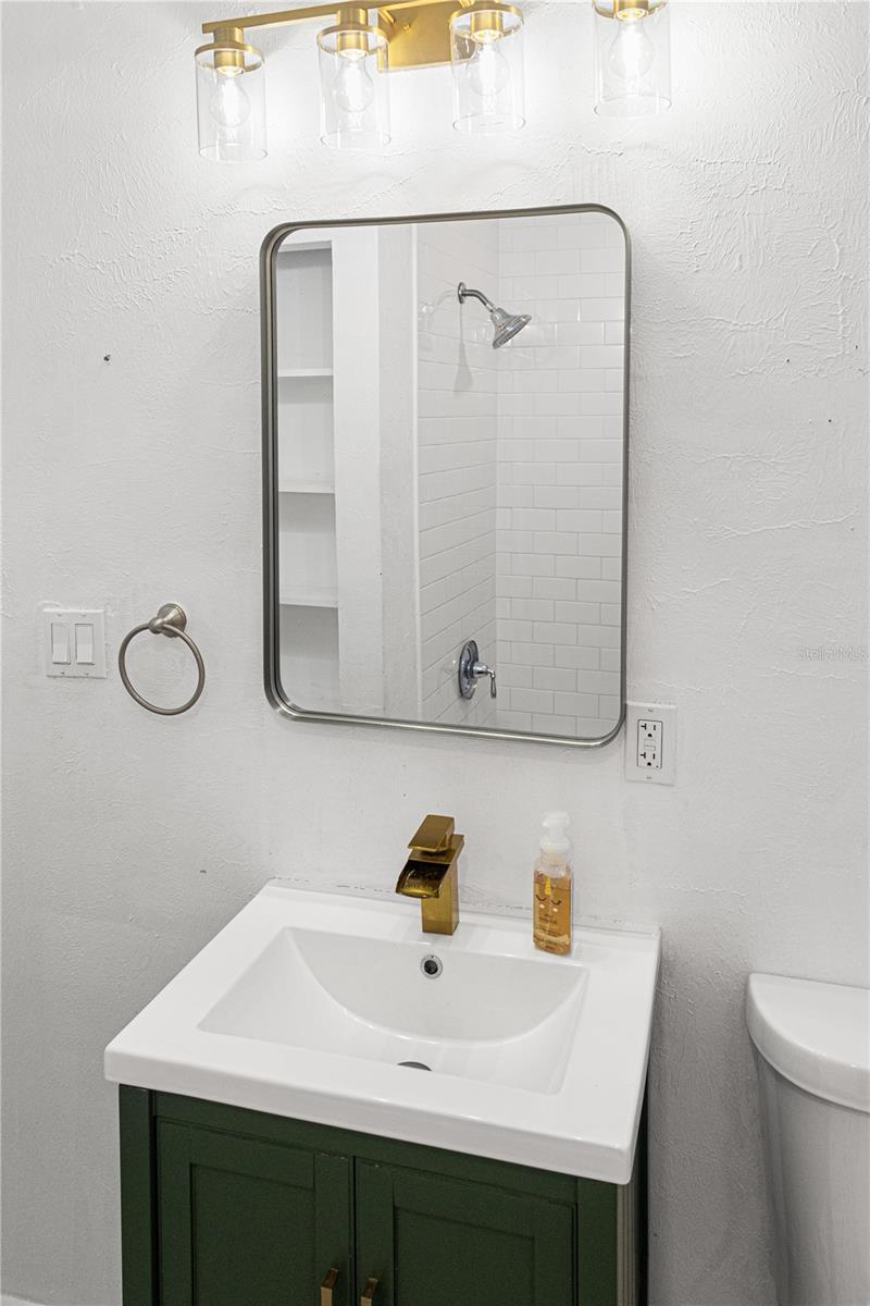 Sleek bathroom featuring updated lighting, framed mirror, and fresh design.