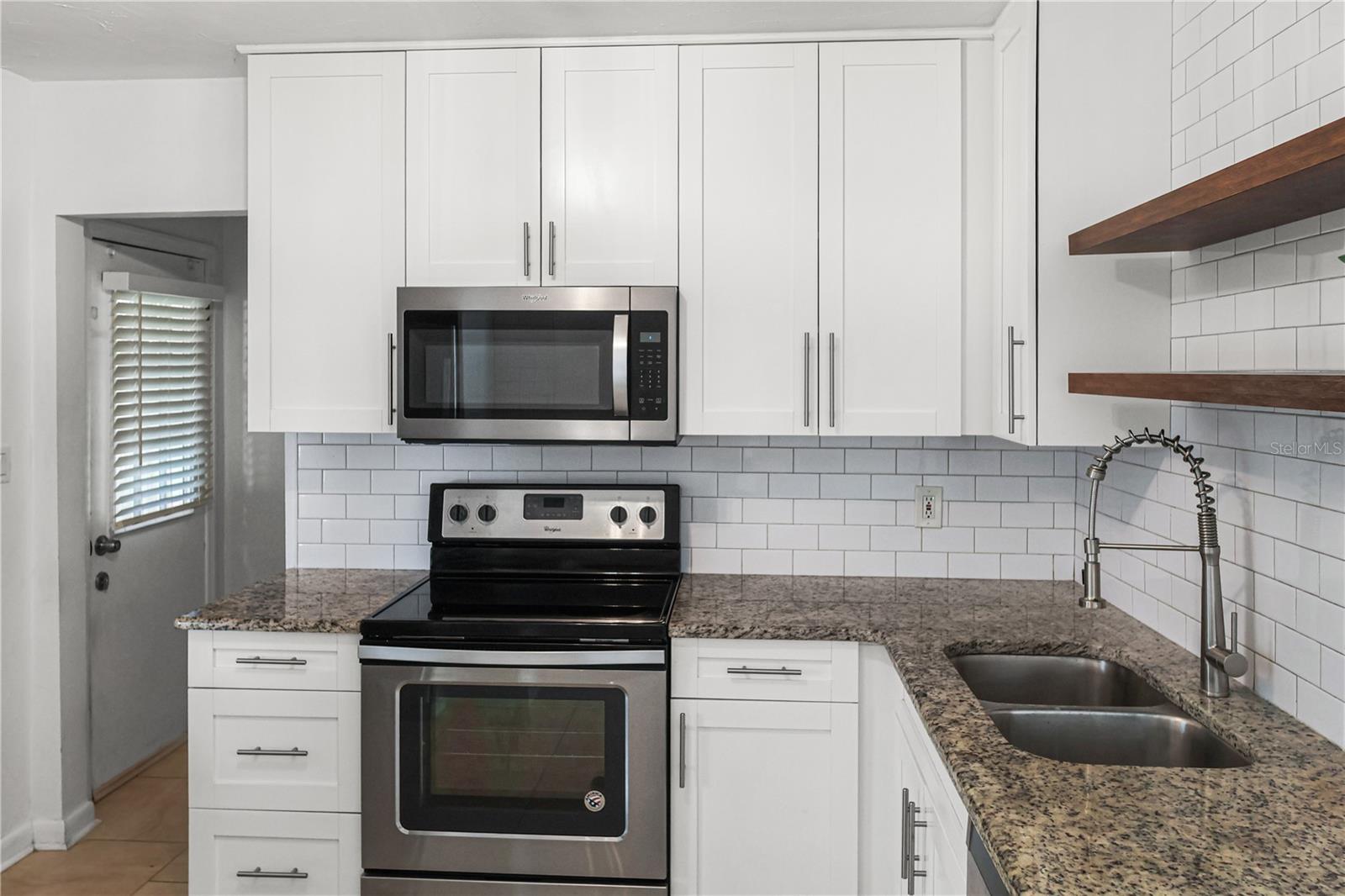 Cook in style, this modern kitchen boasts stainless appliances, granite counters, and open shelving for a designer touch.