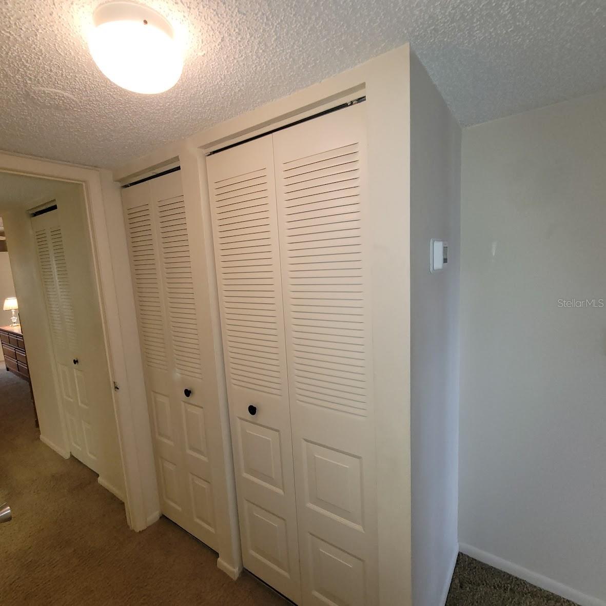 This Hallway between the bedrooms has a walk-in closet for the Primary bedroom, a linen closet, and a utility closet for the Water Heater and HVAC system.