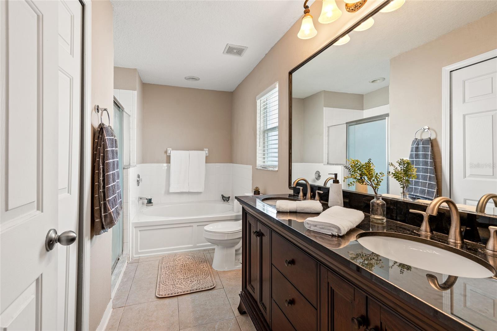 nicely upgraded primary bath with dual sinks, soaking tub, and separate shower
