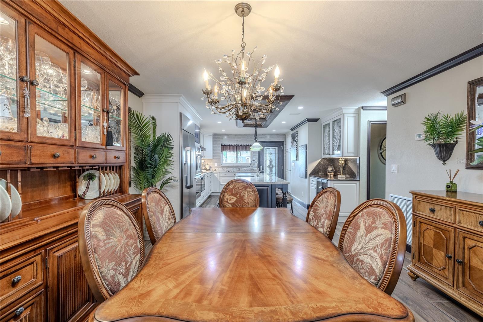 The formal dining area brings warmth and style, with chandelier lighting and an open flow into the kitchen and living spaces.