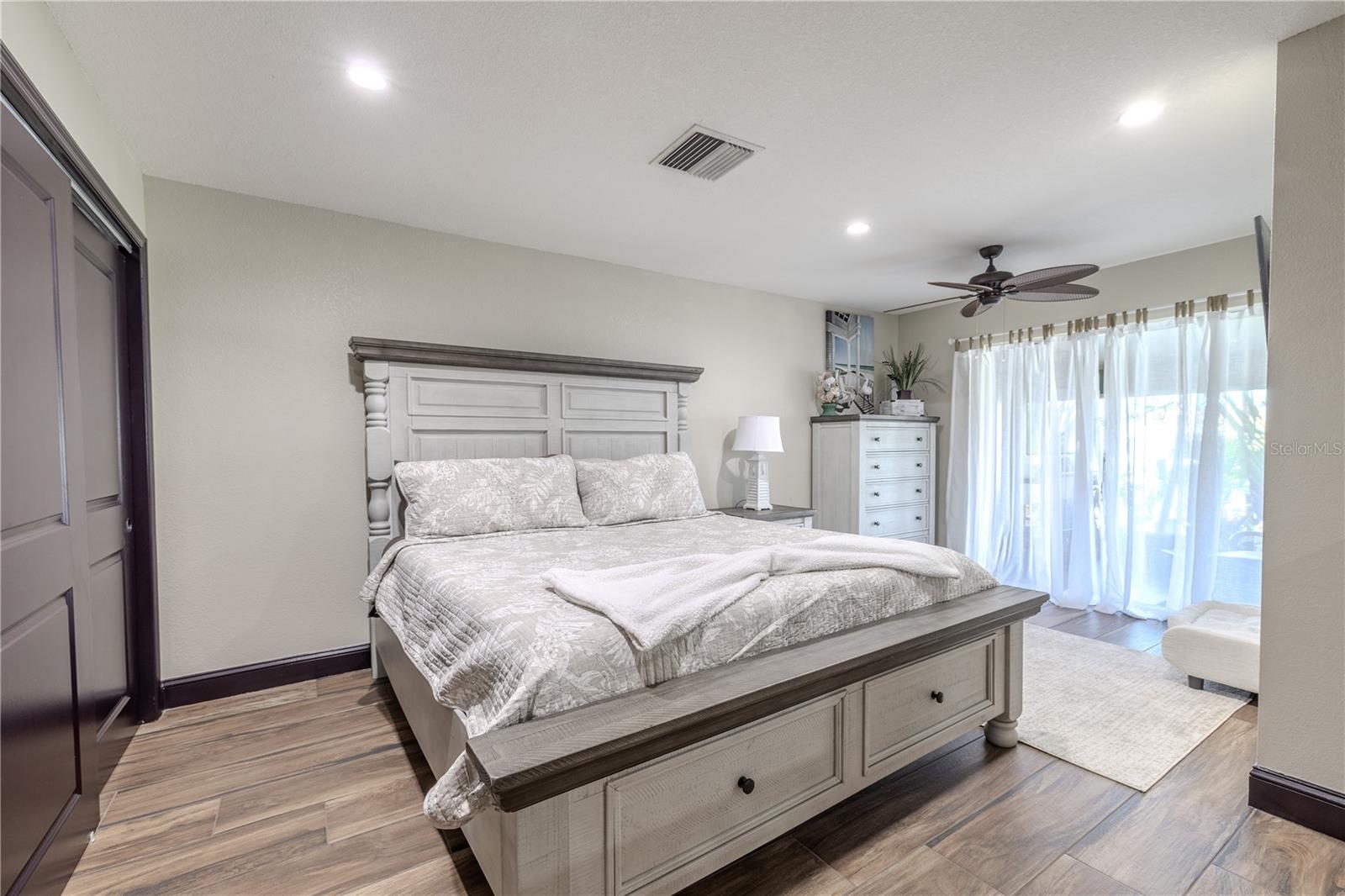 The primary bedroom feels open and inviting with warm natural light and ceramic tile flooring.