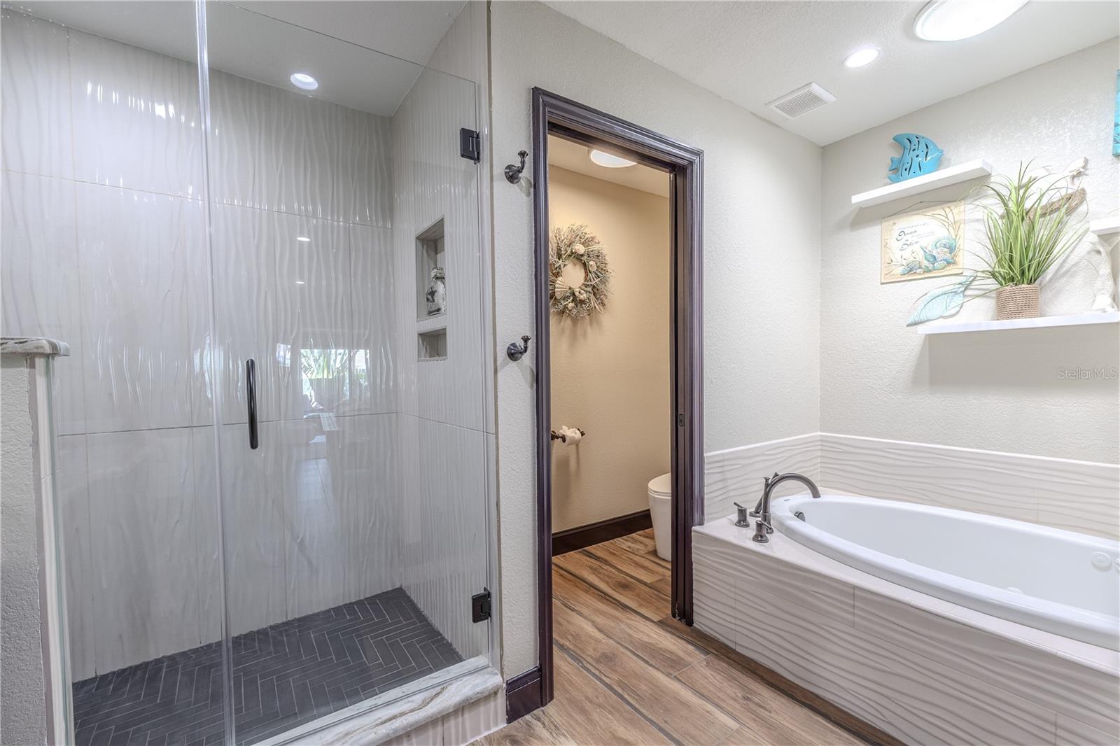 The primary walk-in shower features a rainfall showerhead, seamless glass enclosure, and elegant tile that extends floor to ceiling for a spa-like finish.