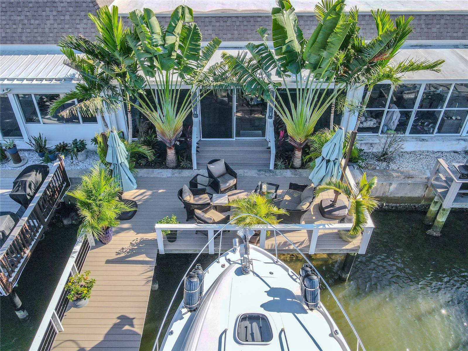The spacious deck offers multiple seating areas for dining or sunbathing, framed by lush palms and scenic waterfront views.