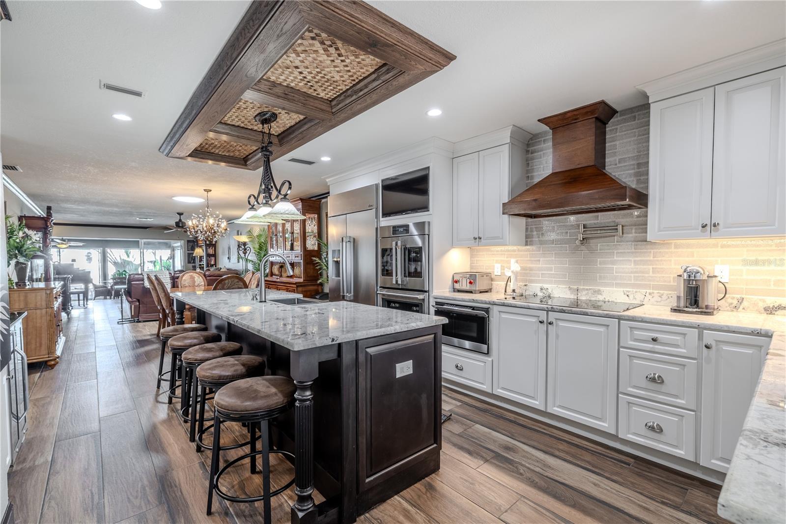 Step inside to an open floor plan where the living area flows seamlessly toward the water, featuring recessed lighting and warm tile flooring throughout.