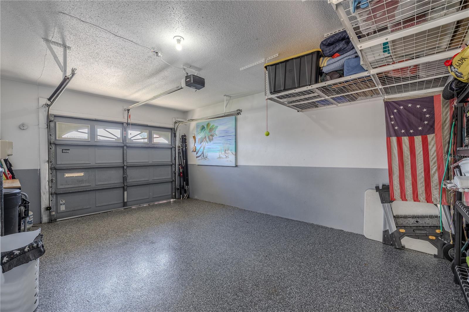 Spacious garage with epoxy-style flooring, overhead racks, and direct access to the courtyard for added convenience.