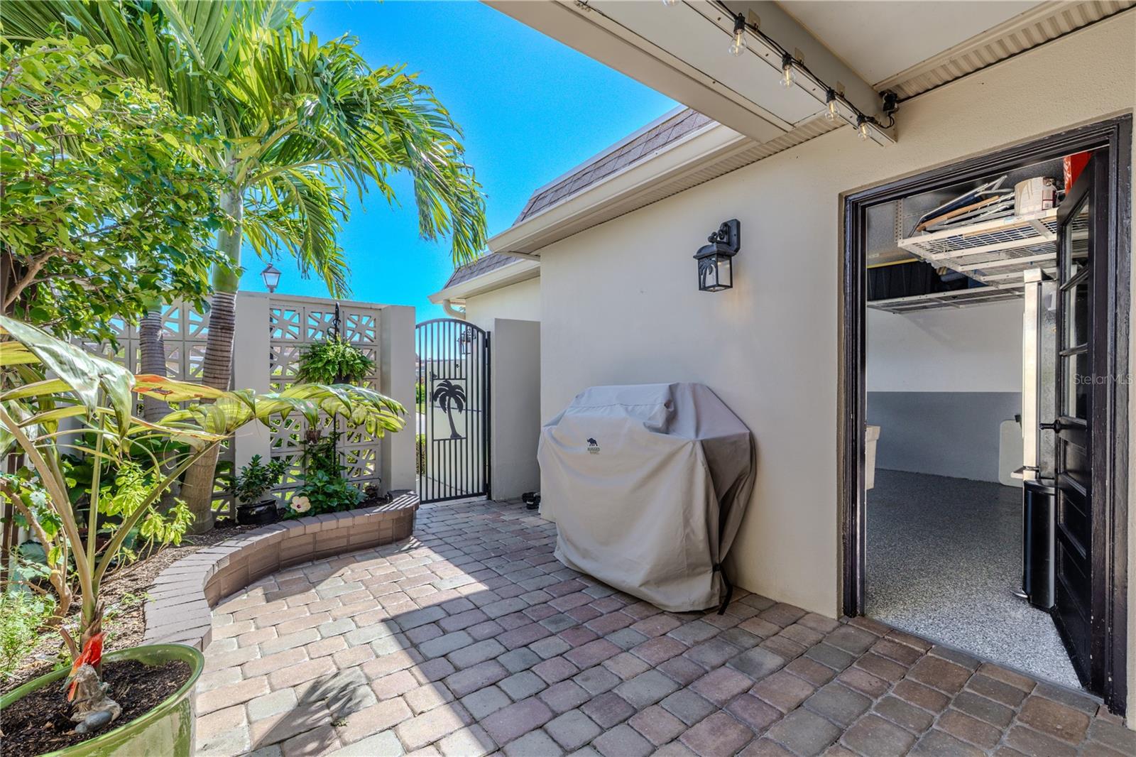 The walkway leading to the front patio features pavers, tropical landscaping, and easy access from both the garage, second bedroom, and main entry.