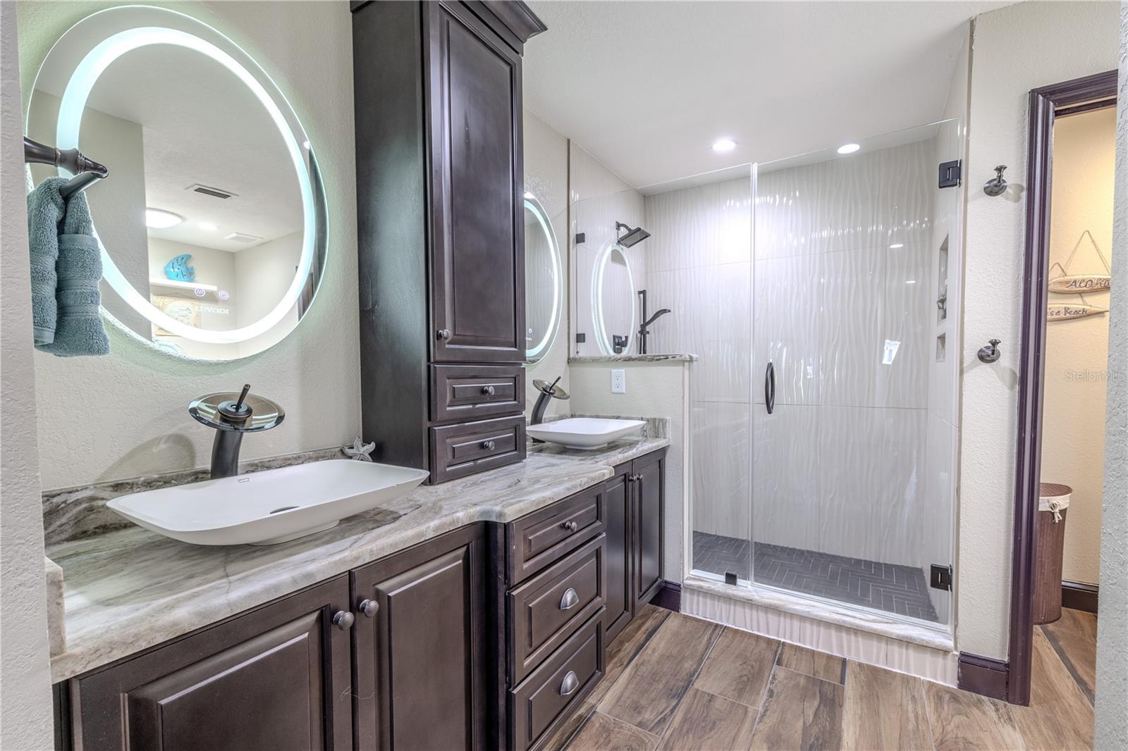 Relax in a spa-like setting featuring a jetted soaking tub, walk-in rainfall shower, and built-in linen storage that keeps everything beautifully organized.