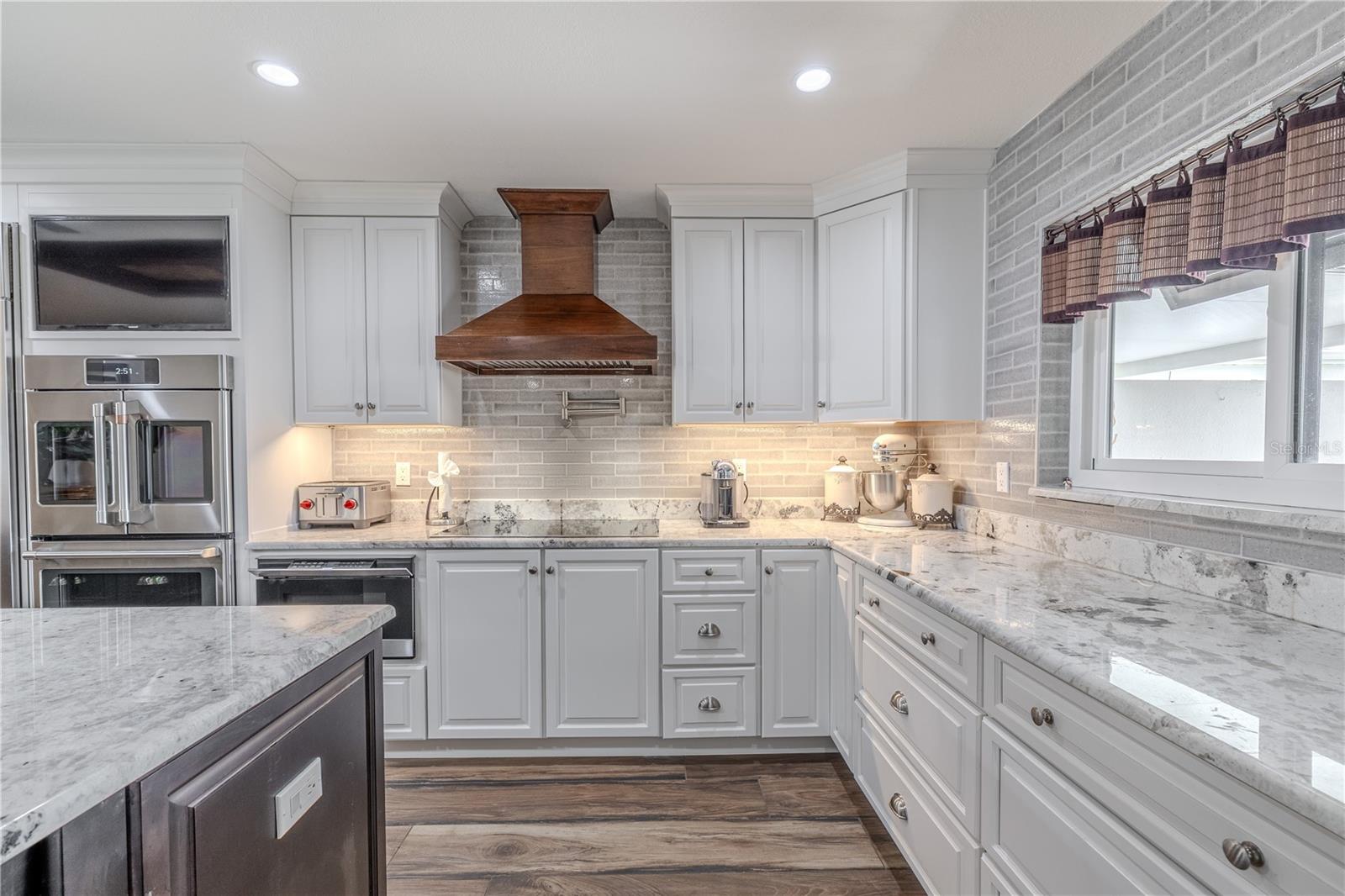 Elegant craftsmanship defines this kitchen, featuring a full brick-style backsplash, soft-close cabinetry, and polished granite counters.