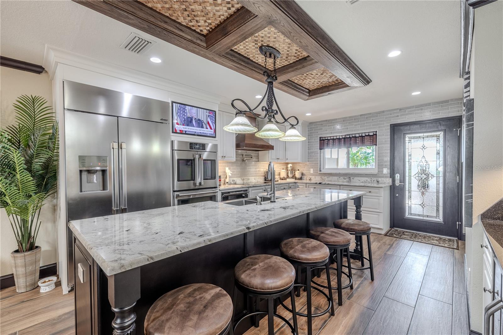Custom cabinetry, under-cabinet lighting, and a pot filler combine functionality and style, while the built-in TV nook keeps the space perfect for entertaining.