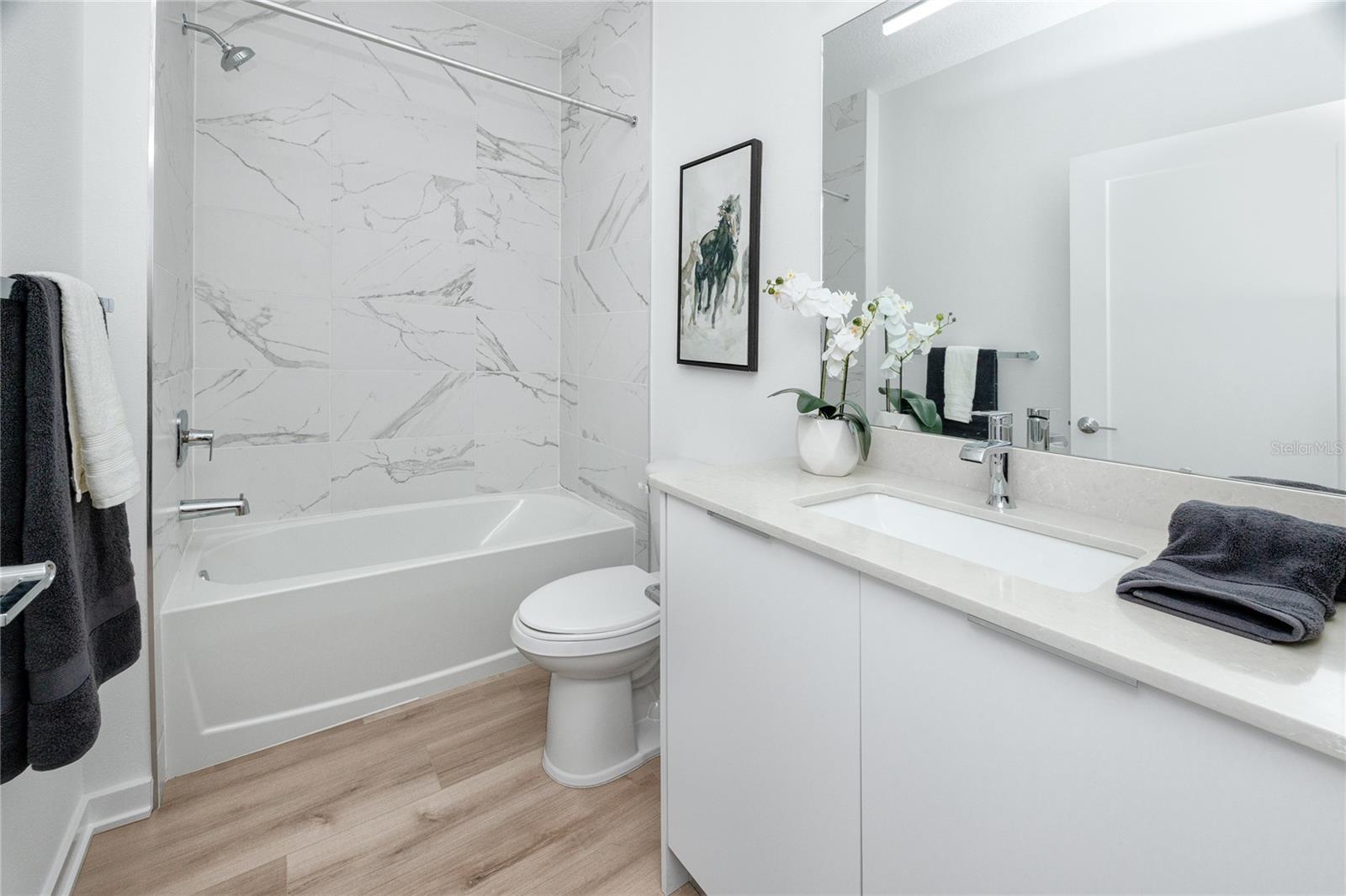 Tub with wall to wall tile in guest bathroom downstairs