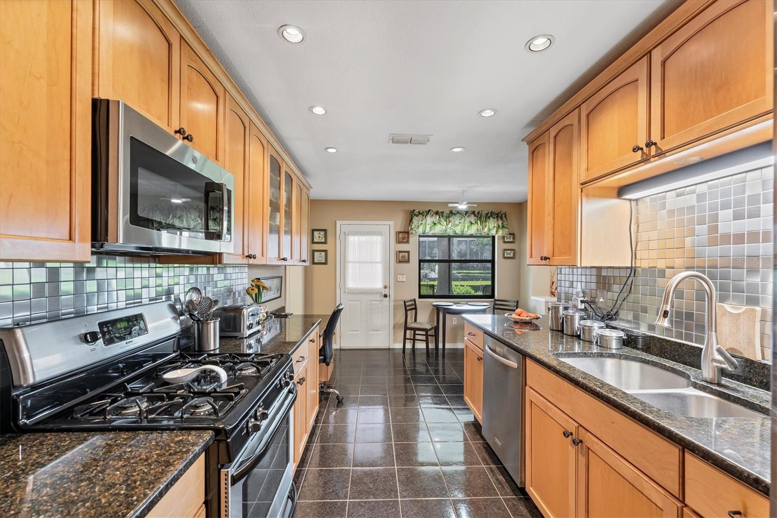 Solid maple wood cabinets, granite countertops, tile backsplash and stainless steel appliances. Huge kitchen with lots of cabinets!