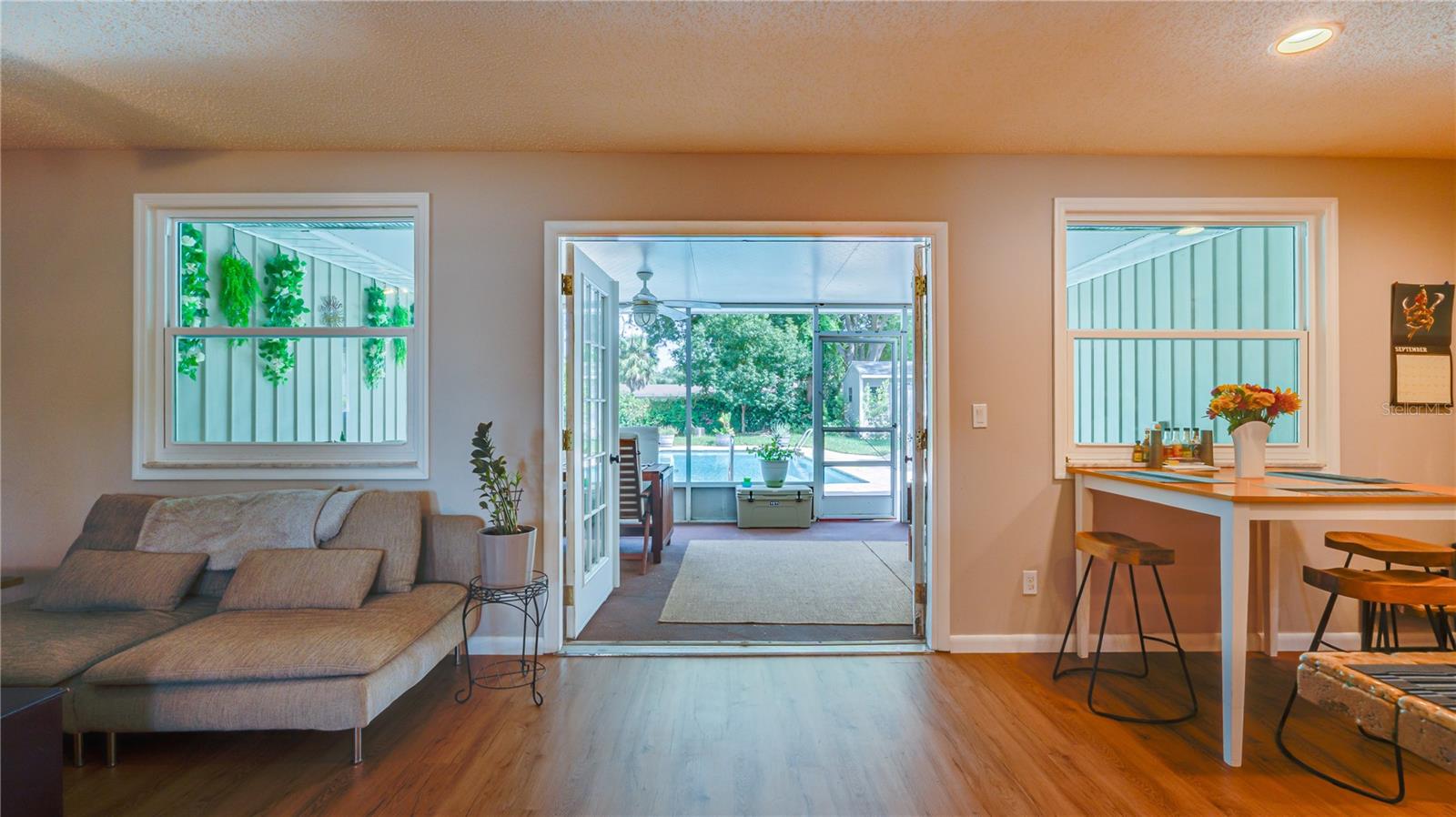 FRENCH DOORS LEADING OUT TO THE SCREENED LANAI AND POOL