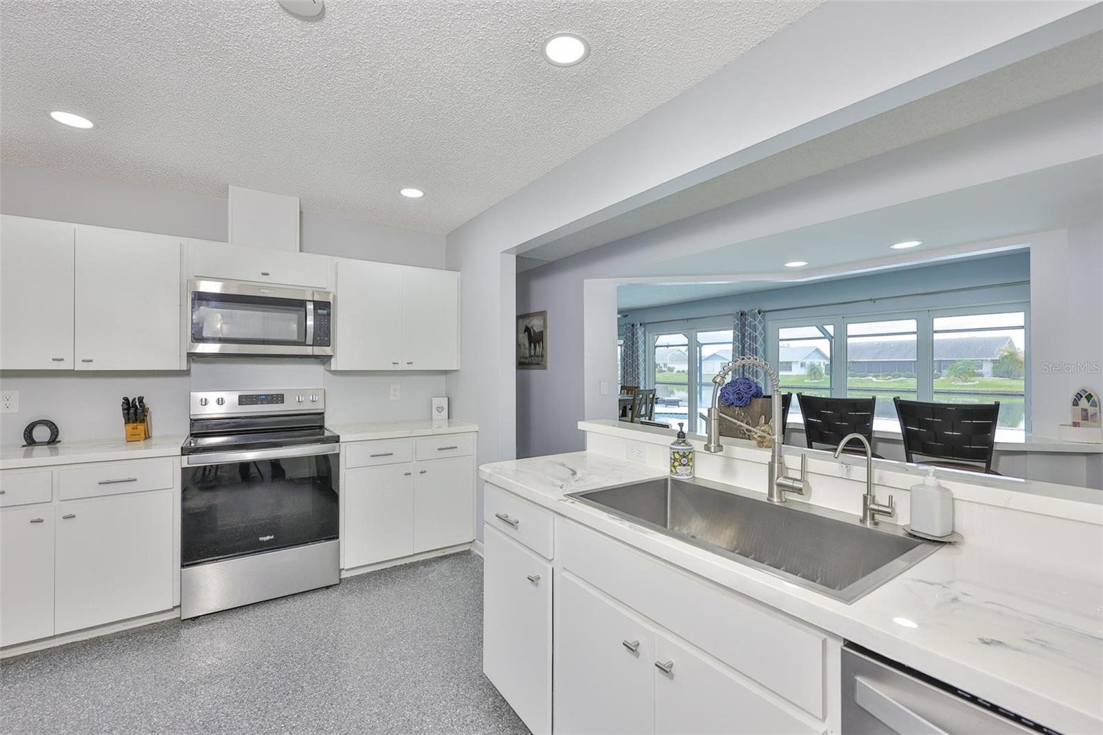 This stylish kitchen is fresh and clean with epoxy flooring and a huge barn sink overlooking a beautiful view of the pool and lake.