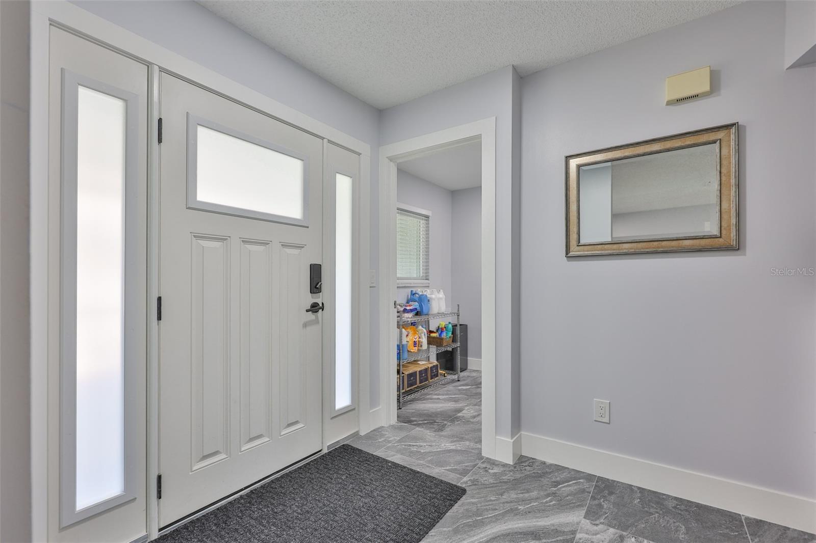 The foyer through the front entrance is bright and spacious. Notice the beautiful large custom door.