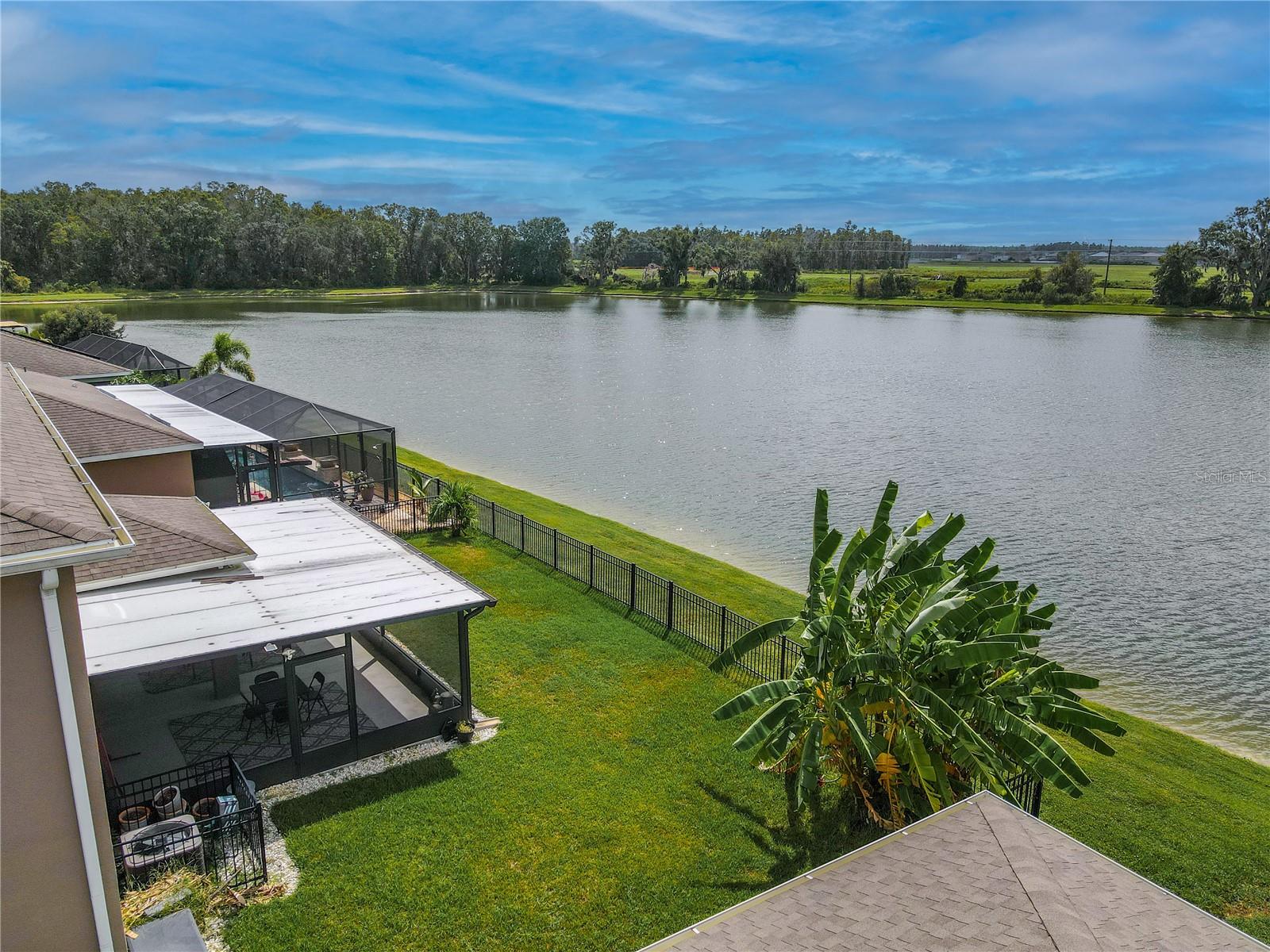 Peaceful backyard retreat overlooking the water, complete with a screened patio and extended concrete pad for grilling or lounging.