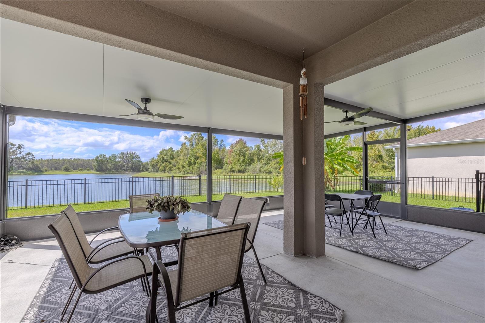 Covered patio with ceiling fan and extended concrete pad, offering the perfect setup for grilling or unwinding by the pond.