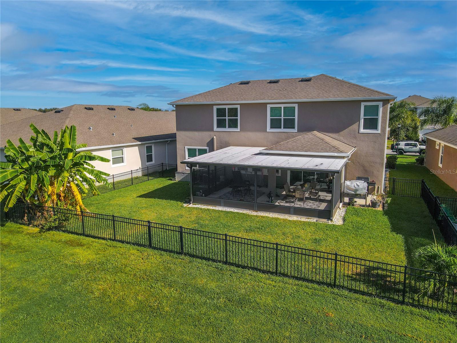 Backyard view showing the fenced yard, lush landscaping, and pond setting for added privacy.
