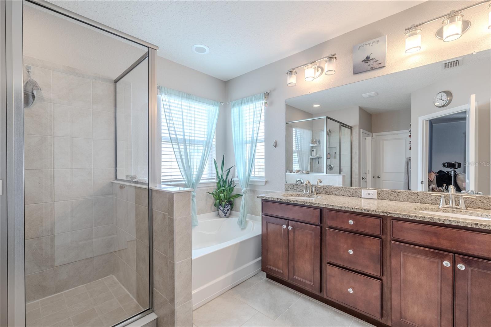 Primary bathroom with granite counters, dual sinks, walk-in shower, and separate soaking tub for a spa-like experience.