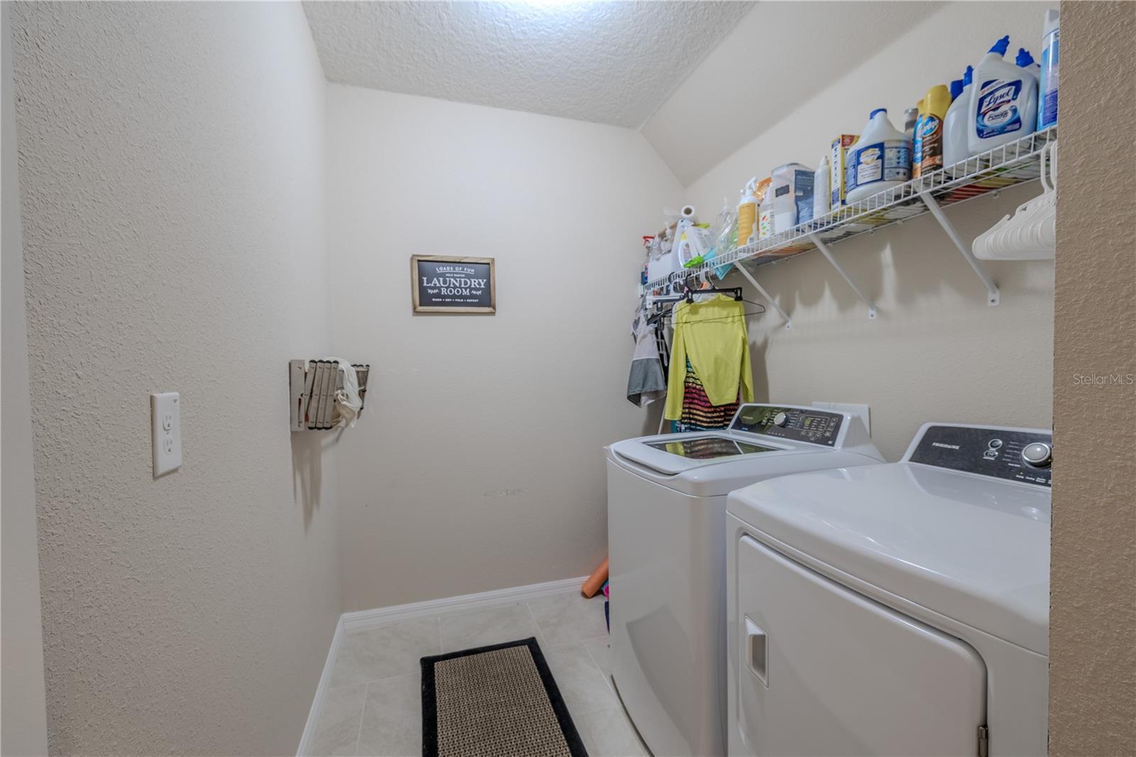 Laundry room with matching Frigidaire washer and dryer set, a utility sink, and plenty of workspace for convenience.