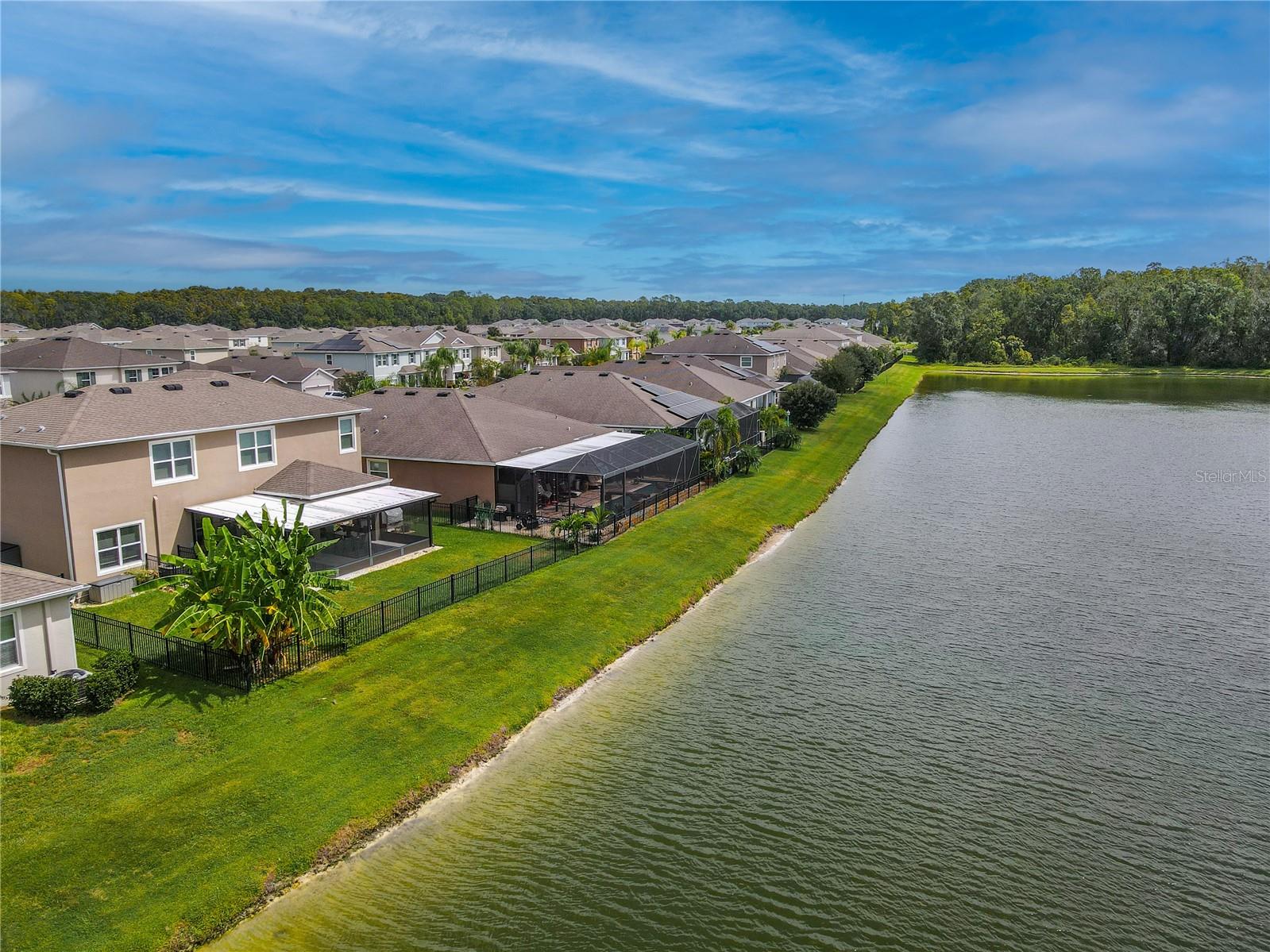 Scenic aerial photo highlighting the tranquil pond behind the home and the beautiful natural surroundings of the neighborhood.