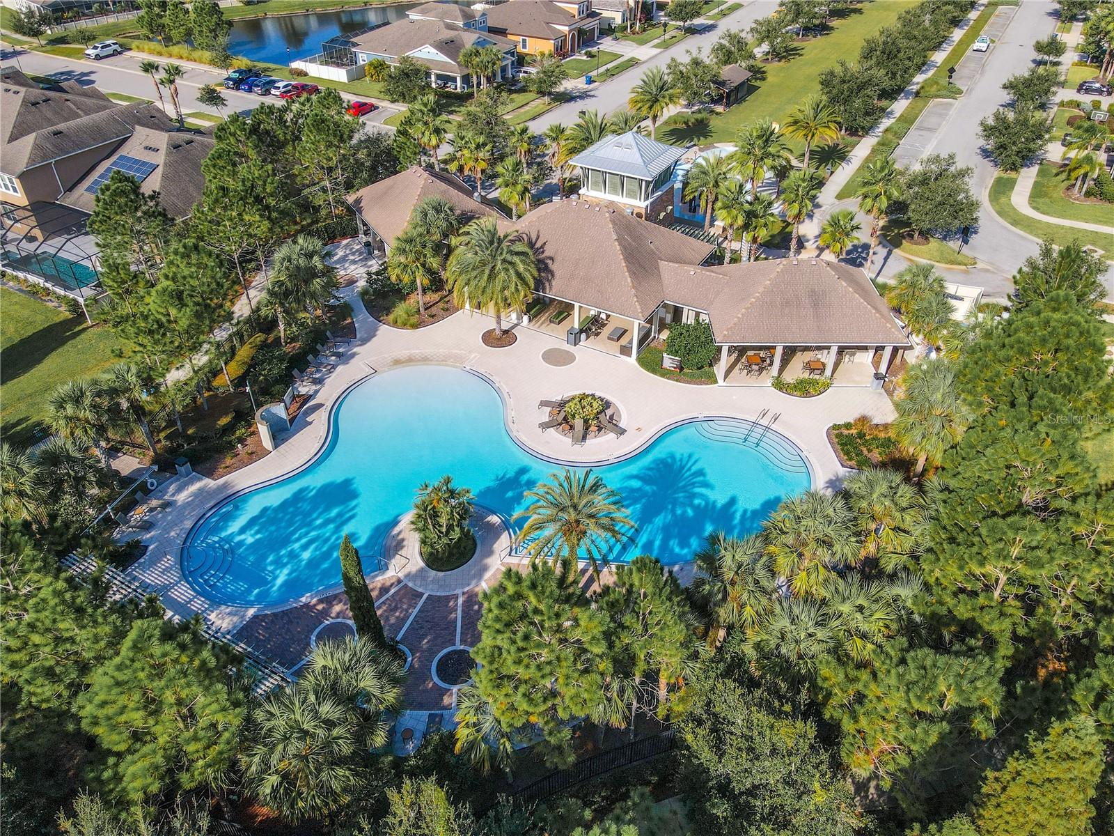 Resort-style community pool surrounded by lush landscaping and plenty of space for lounging and relaxation.