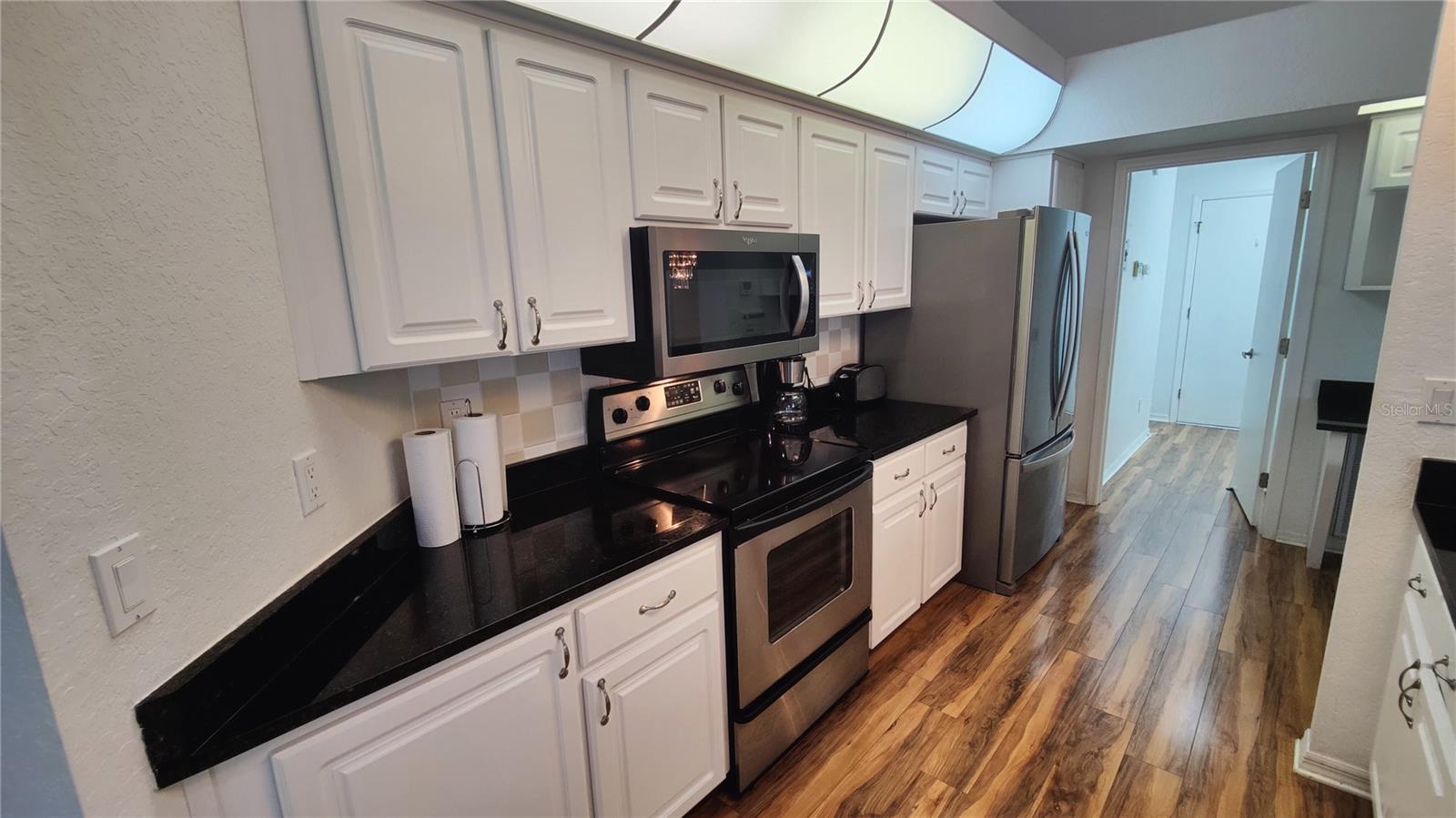 Large kitchen has bright diffused lighting, stainless steel appliances, new dish washer, lovely wood floord that run throughout the home.  Custom cabinets - granite countertops and backsplash match the countertops in the bathrooms.