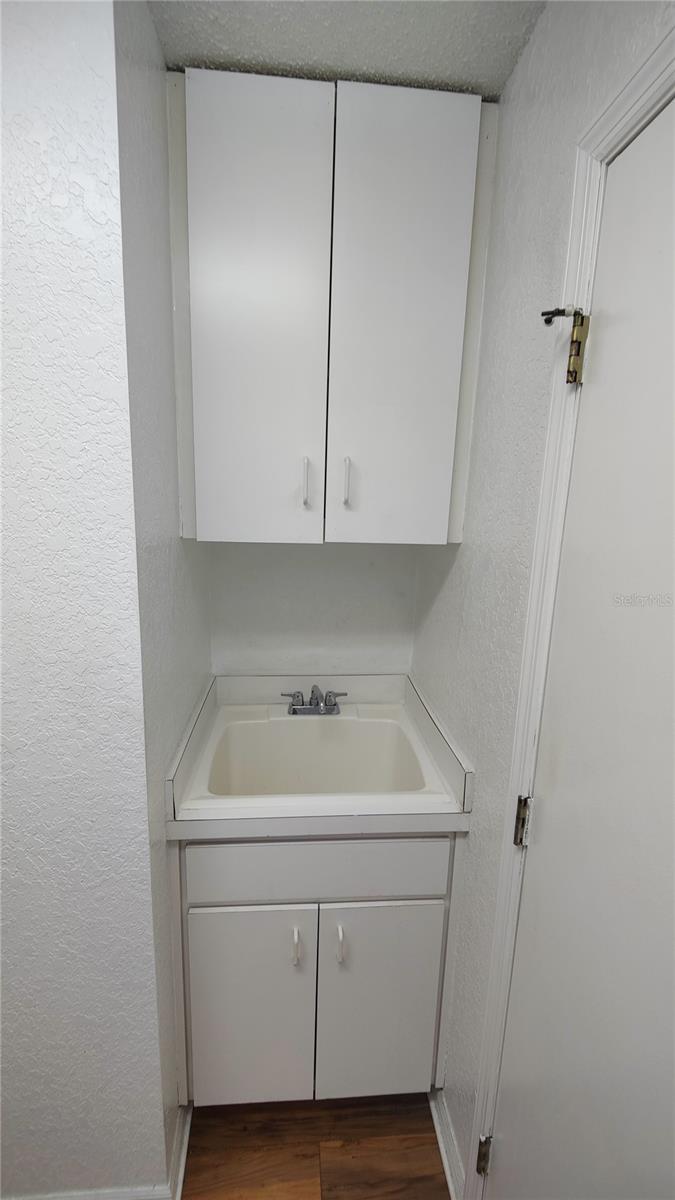 Laundry room sink has more storage cabinets above and underneath it.