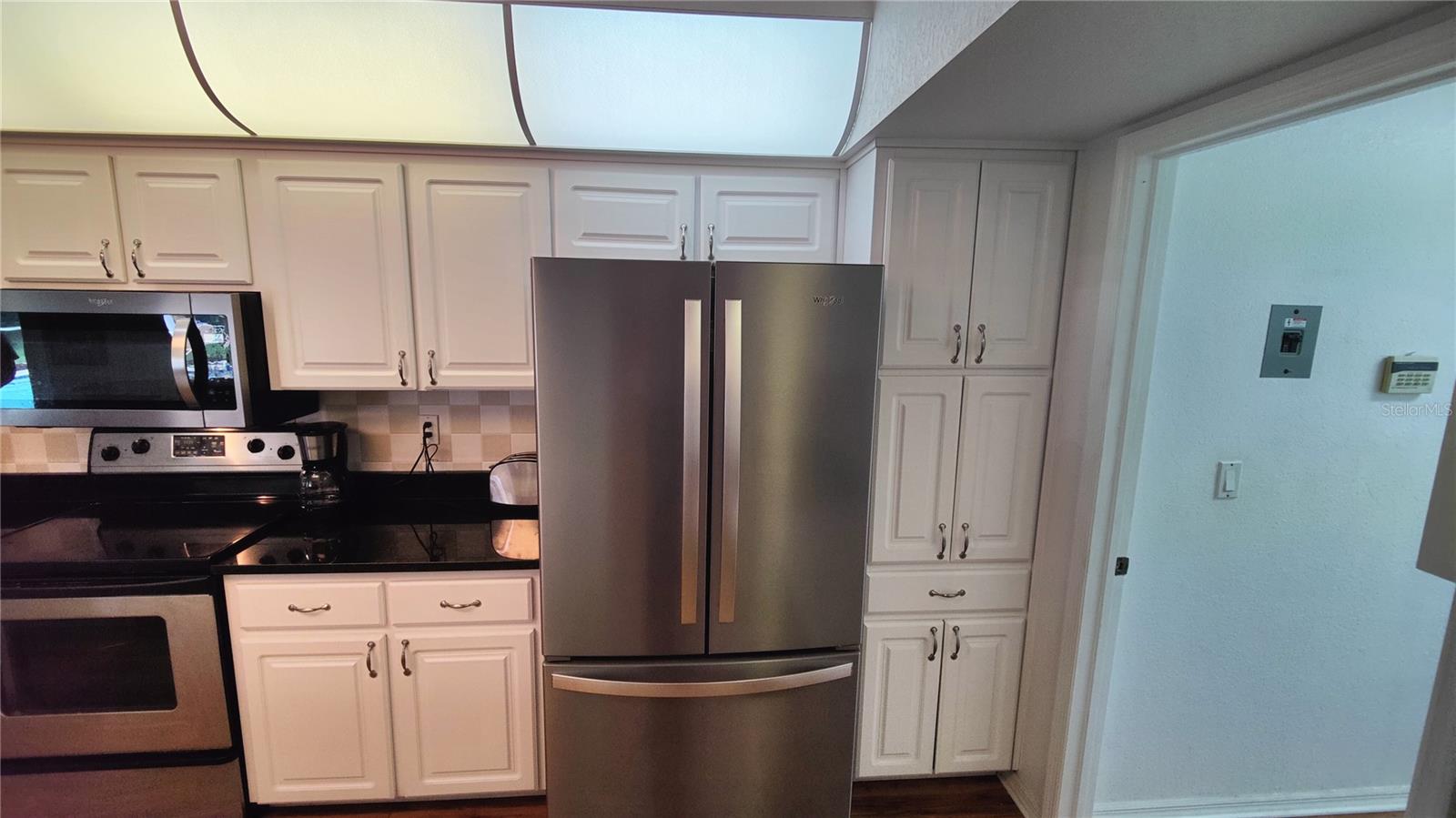 Kitchen double door refrigerator has a large slide out drawer freezer underneath.  New range features an easy clean smooth cooking surface. Kitchen has lots of custom storage cabinets and drawers for easy organization