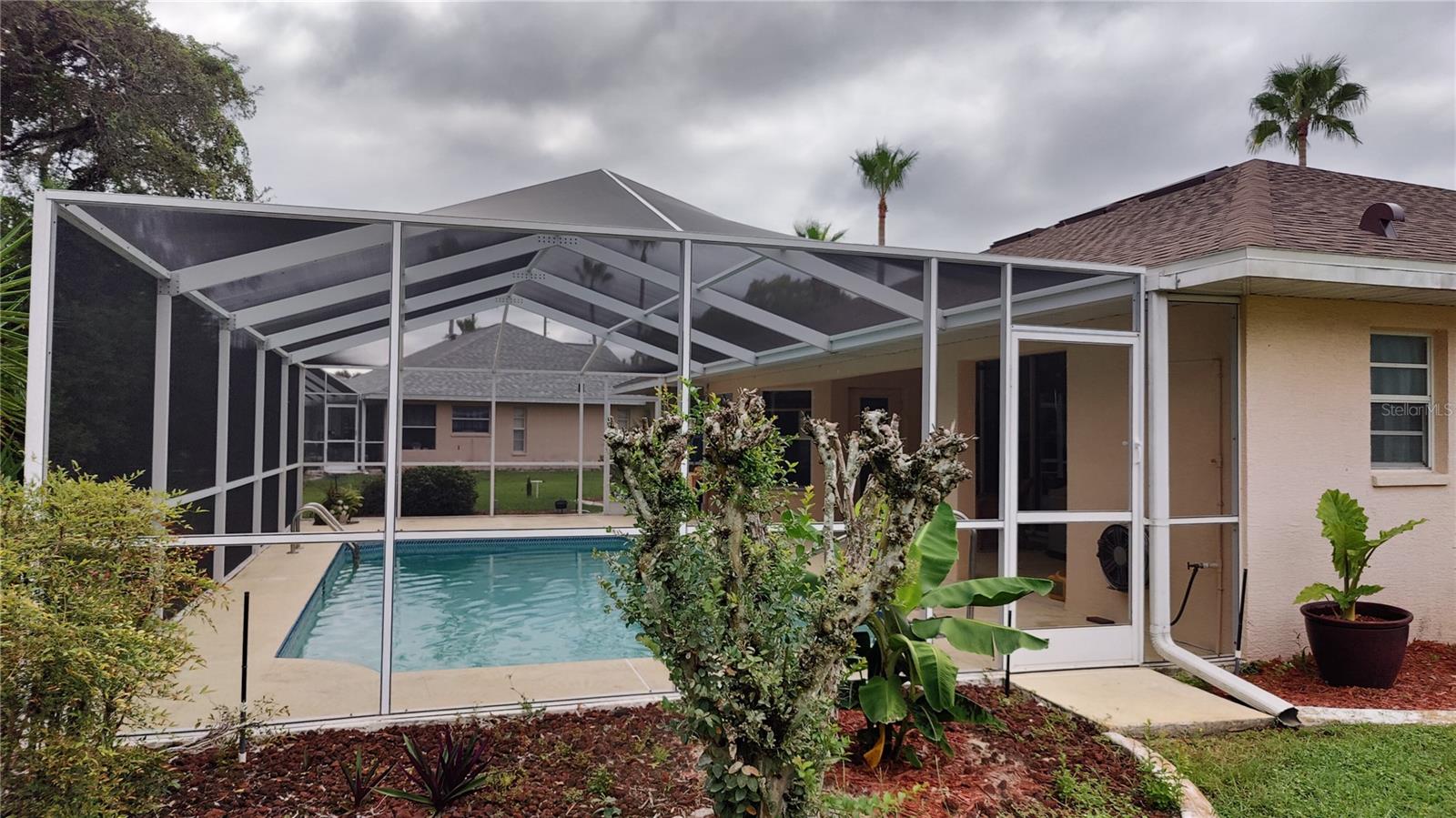 Side view of pool,  Outside shower is located on wall just inside the screened roor behind the changing room 1/2 bath.